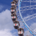 Ferris wheel with colorful gondolas against a cloudy blue sky.