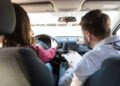 Rear view of mid adult teacher pointing while woman parking car
