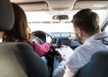 Rear view of mid adult teacher pointing while woman parking car