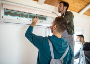 Repairman team installing air conditioner at client's home