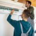 Repairman team installing air conditioner at client's home