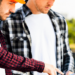 Two men in hard hats examining a tablet, discussing plans on a construction site.