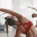 Fit females doing warmup exercises in a fitness class at a center. Training coach guiding a class with motion and movement. Youth athletic females doing yoga and pilates, focused on health and cardio