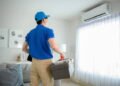An Asian young Technician service man wearing blue uniform checking ,  cleaning air conditioner in home