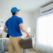An Asian young Technician service man wearing blue uniform checking ,  cleaning air conditioner in home