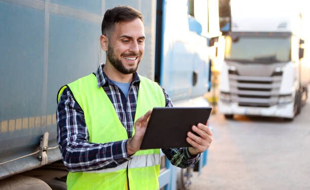 Truck driver in front of his trucks. About 30 years old, smiling Caucasian mid adult man.