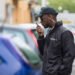 Young Male Security Guard In Black Uniform Using Walkie-Talkie On Street