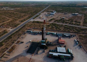 Fracking Drilling Rig Creating Gas or Oil Well Silhouetted at Dusk Under a Dramatic Sunset Sky