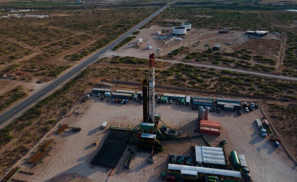 Fracking Drilling Rig Creating Gas or Oil Well Silhouetted at Dusk Under a Dramatic Sunset Sky